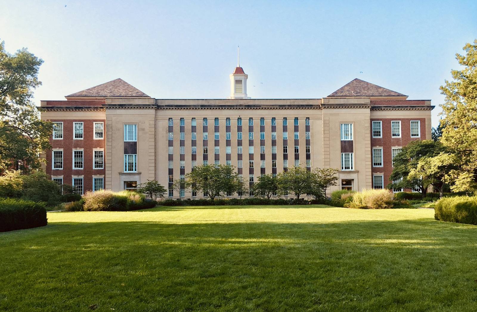 A university building with a wide green lawn