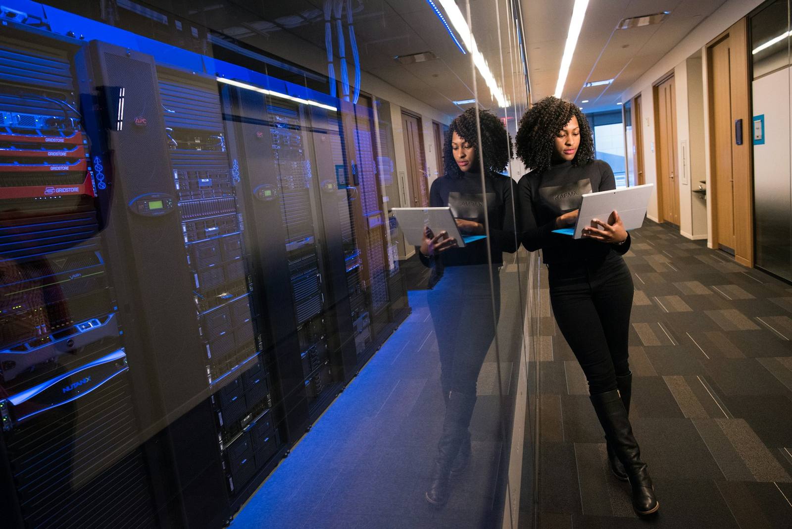 An IT professional working with a tablet in a server room