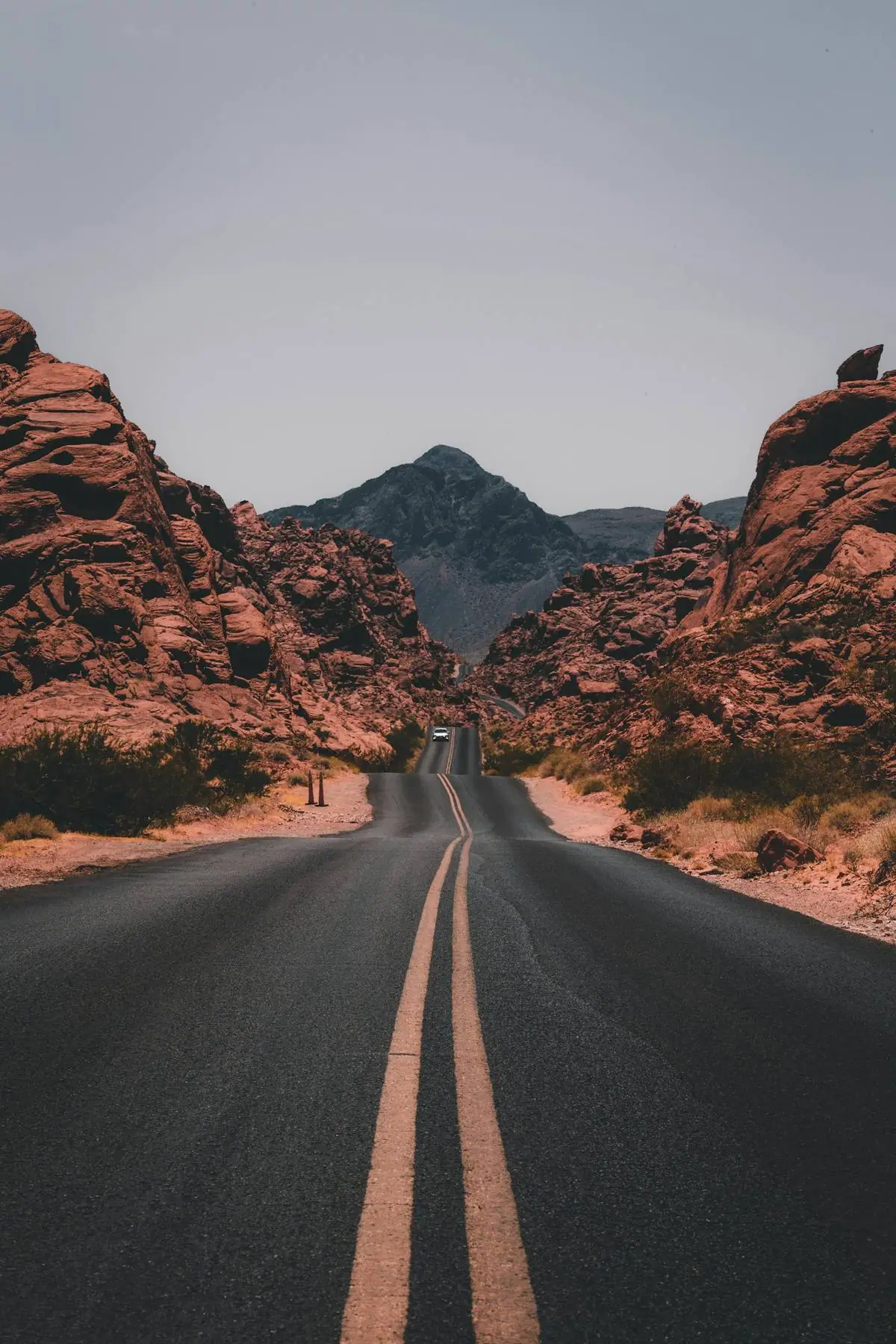 An open road leading toward red rock mountains