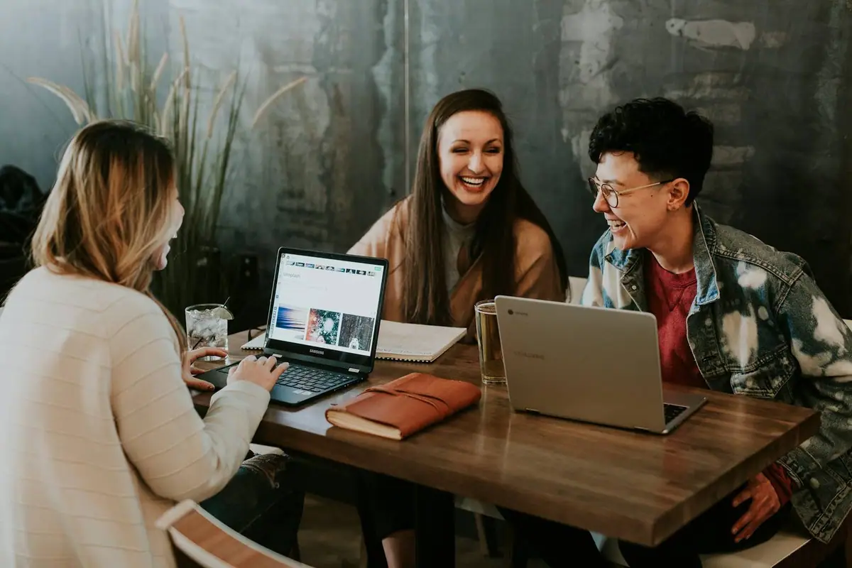 Colleagues laughing together around laptops