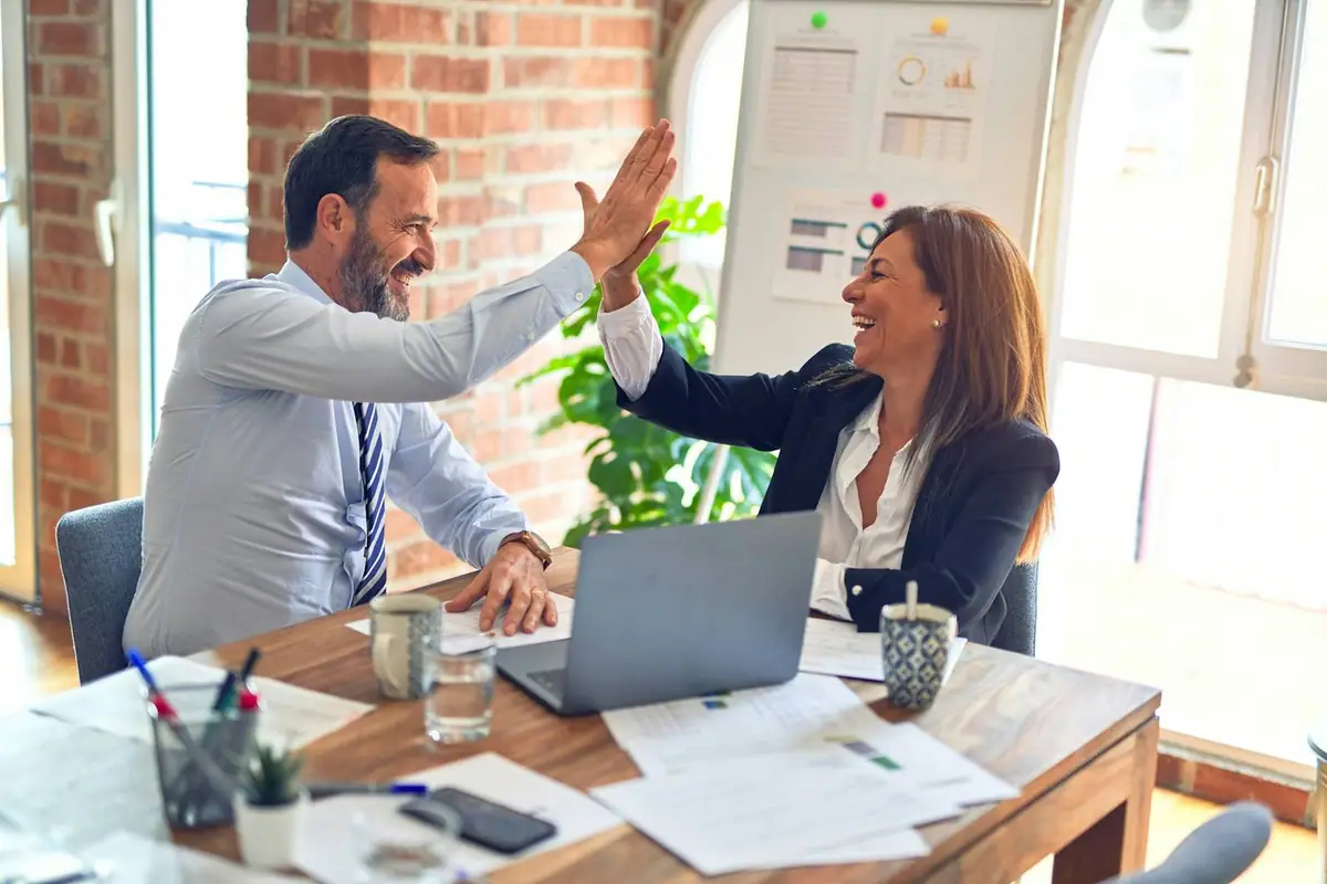 Colleagues celebrating with a high five in a bright office