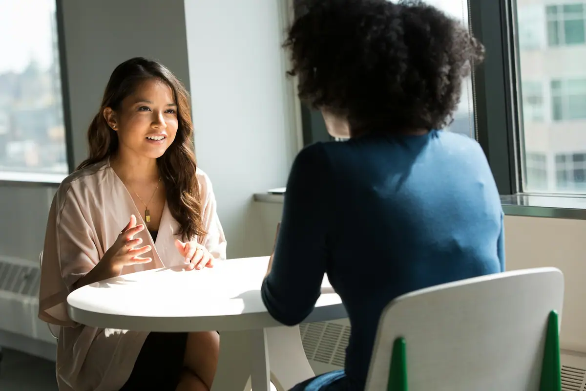 A smiling professional leading a one-to-one conversation by a sunny window